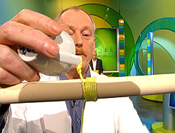 Experimentator Theo Schmitz zeigt die Tasse, die sich mehrfach um den Besenstiel gewickelt hat; Rechte: WDR-Fernsehen 2003